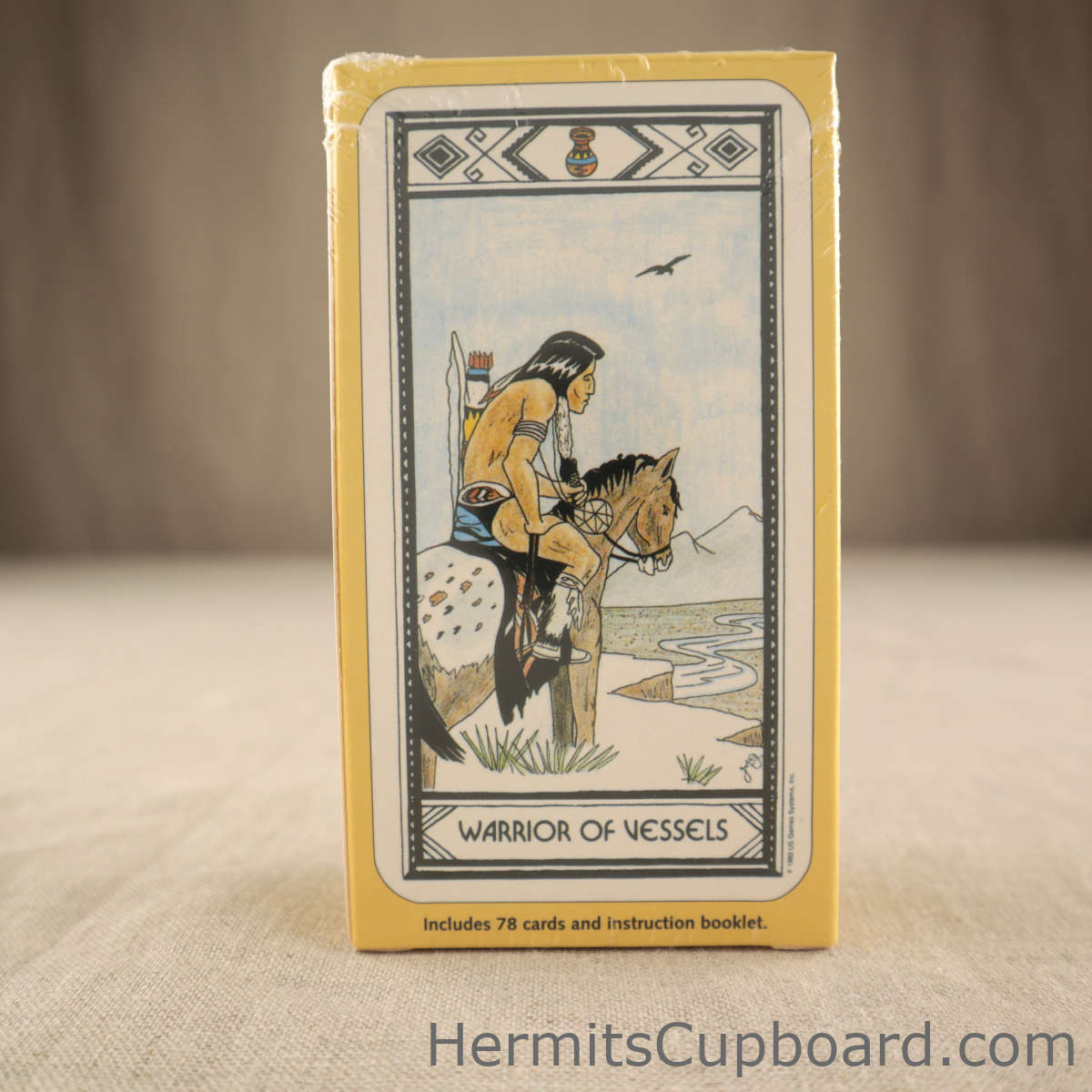 Native American Tarot deck back of box showing the warrior of vestles card art of a warrior scout on horseback looking over a valley with a river running through it